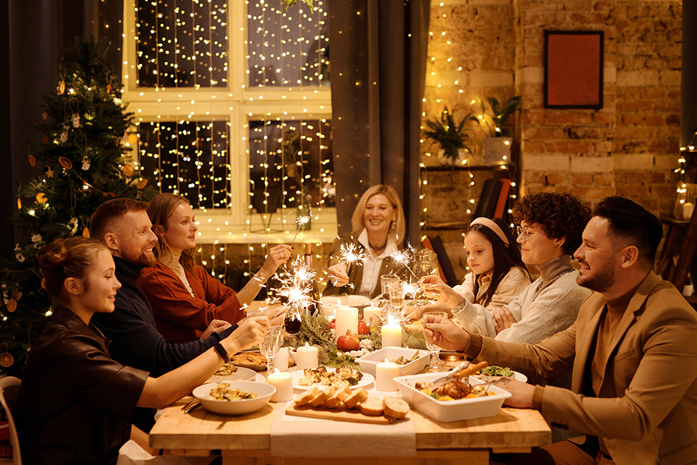 Amici a tavola per Natale, luci soffuse, lampadine e tavola imbandita con persone sedute