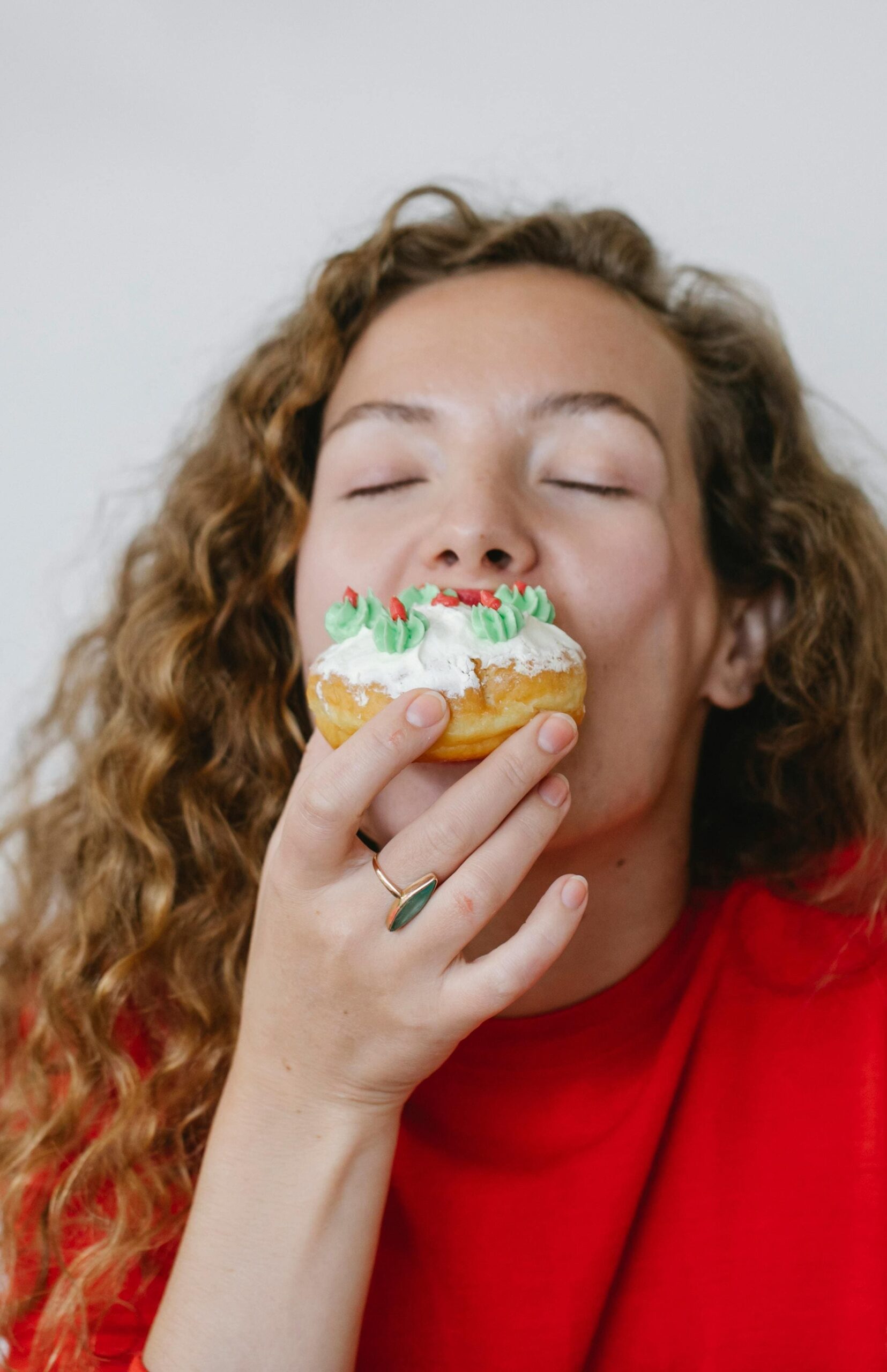 ragazza con maglione rosso che addenta donuts al cioccolato