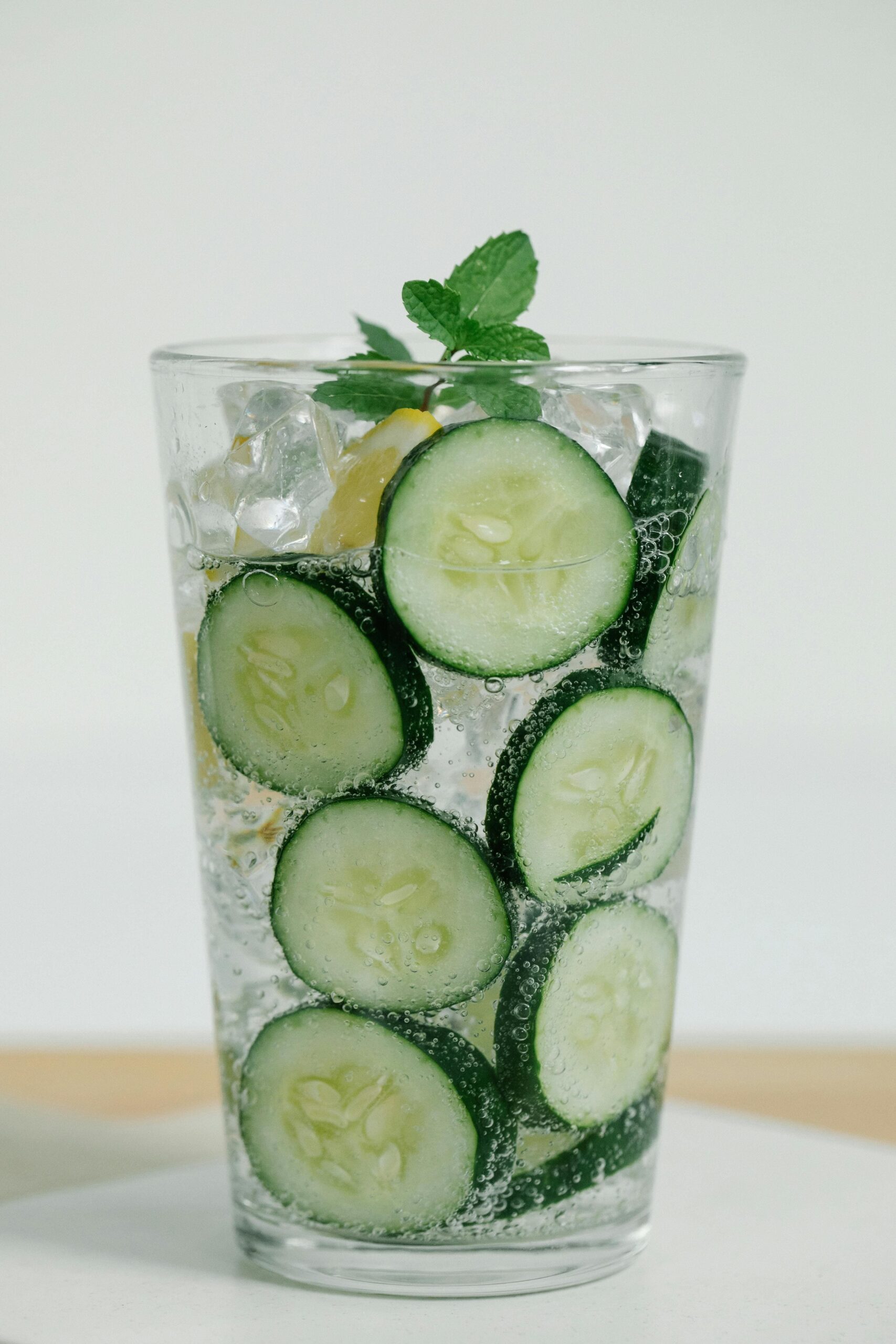 Bicchiere trasparente con acqua, cetrioli e menta